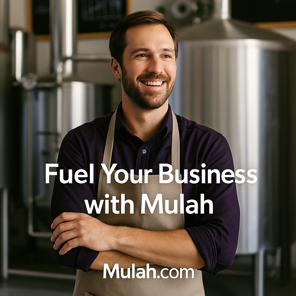 Smiling manufacturing business owner standing confidently in an industrial facility, wearing an apron, with the text “Fuel Your Business with Mulah” and the Mulah.com logo.