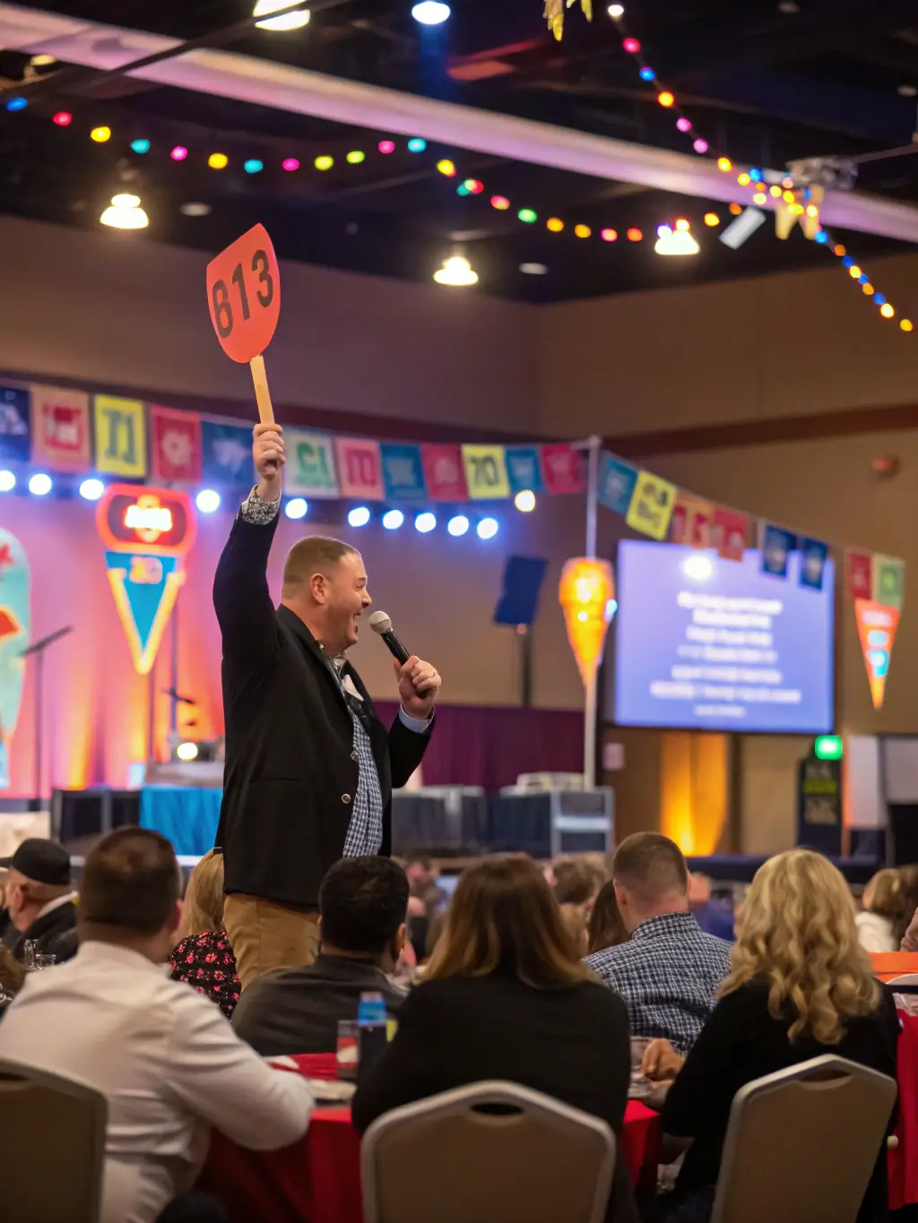 A professional auctioneer confidently addressing a room full of bidders, showcasing their expertise and success in driving high sales.
