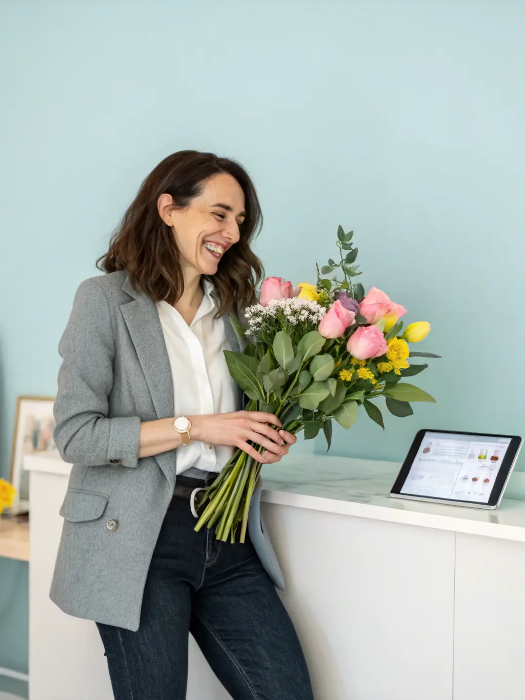 A florist using a tablet to manage online orders and inventory in a modern, well-organized flower shop, emphasizing the efficiency gained through Mulah's funding.