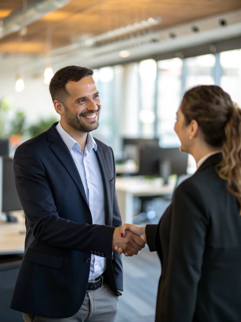 A professional businessman smiling and confidently shaking hands with a Mulah representative in a modern office setting, symbolizing trust and partnership.