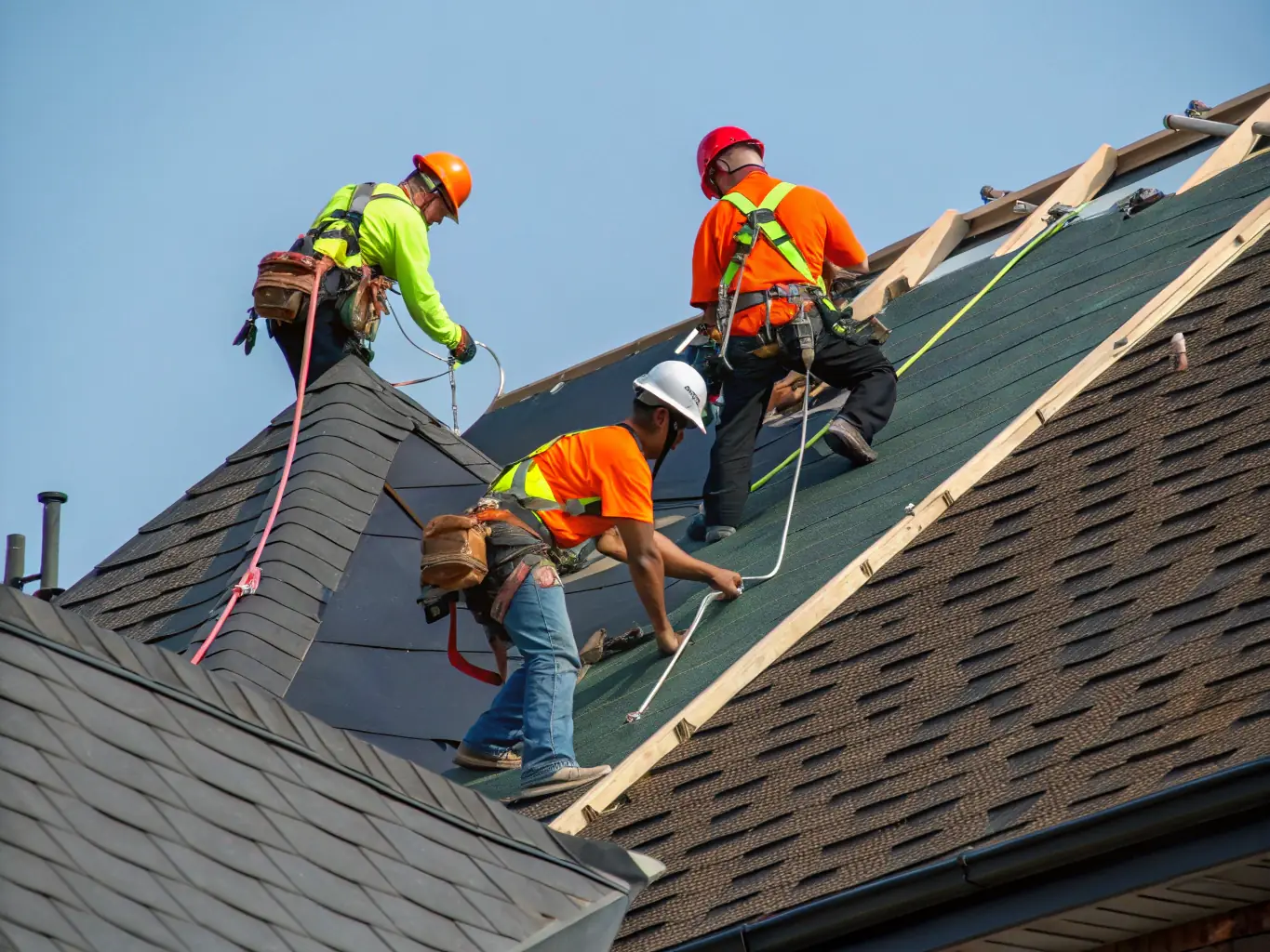 A roofing crew working efficiently on a residential roof, highlighting the importance of timely funding for labor and materials in roofing projects.